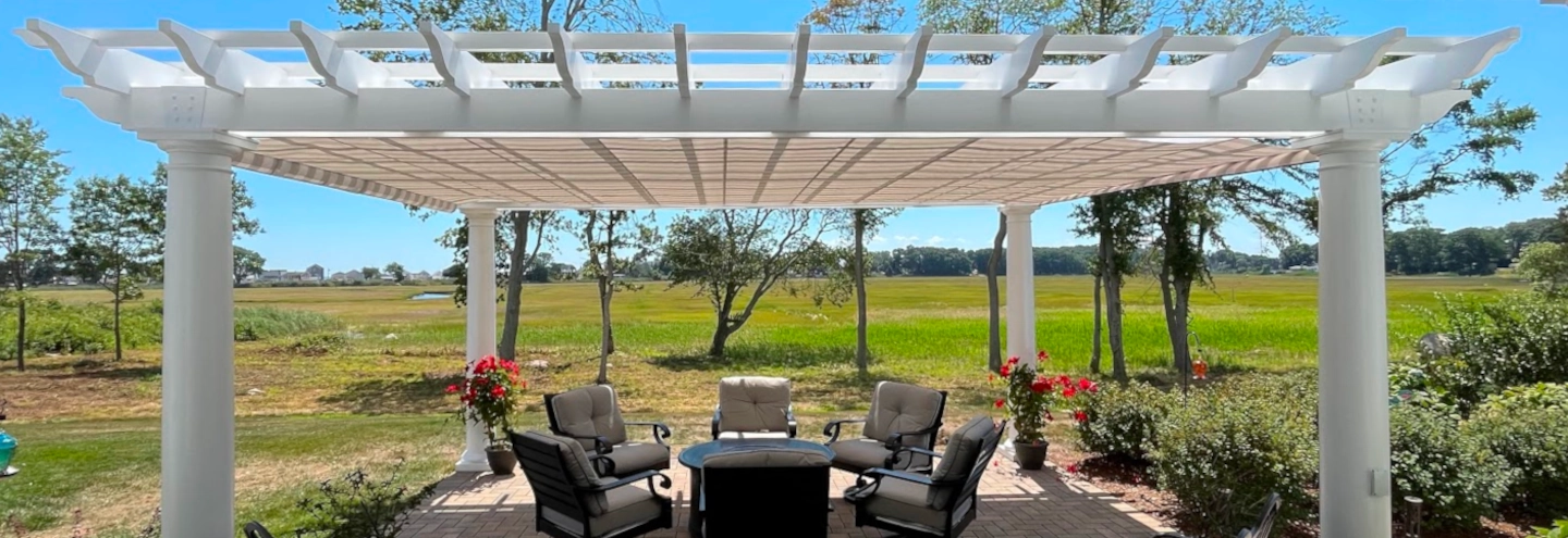 A pergola with a striped fabric roll-up shade