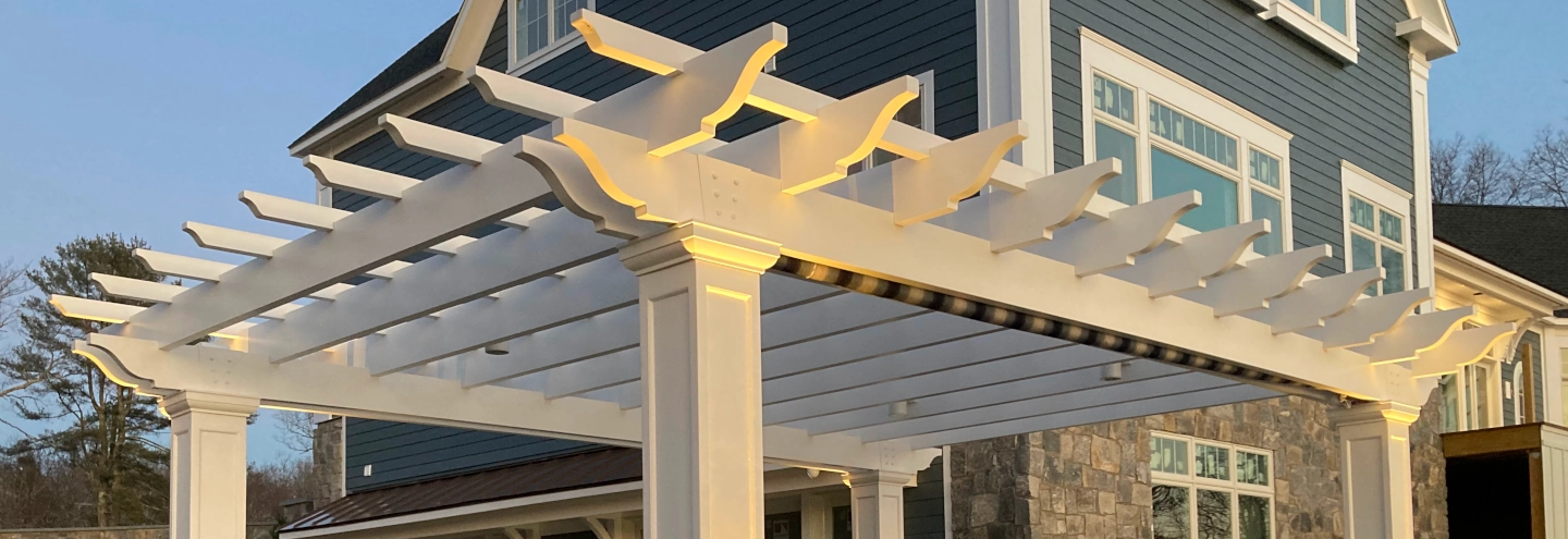 A pergola with a striped fabric roll-up shade